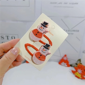 Detail of Christmas snowman hair clips with glitter texture and red ribbon base