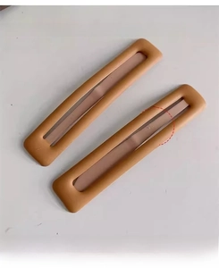 Détail de deux pinces à cheveux rectangulaires mates de couleur caramel chic