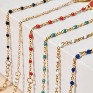 Detailed macro view of colorful enamel beads on gold-plated stainless steel chains
