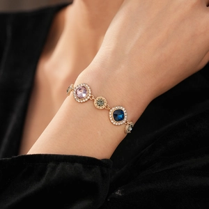 Detail of vintage gold bracelet with colorful gems and pavé crystals on a black sleeve