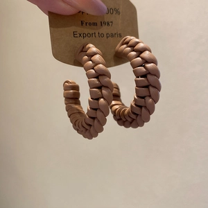Detailed view of hand-woven leather C-shape hoop earrings in rich caramel brown color