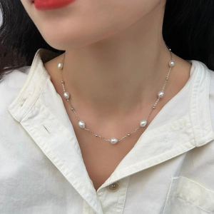 Close-up of minimalist freshwater pearl necklace with silver chain on model neck