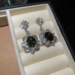 Macro view of vintage silver flower earrings featuring oval green stones and zircon accents