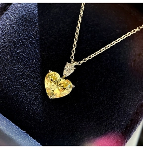 Macro detail of silver heart necklace featuring a brilliant yellow gemstone pendant