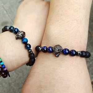 Detail view of adjustable tiger eye and obsidian beaded bracelets with metal wolf head
