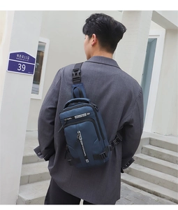 Rear view of a man wearing a navy blue crossbody bag in a bright urban street setting