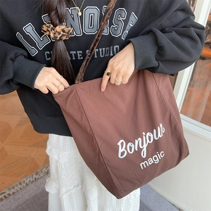 Close-up of brown canvas tote bag featuring leopard print straps and Bonjour Magic text