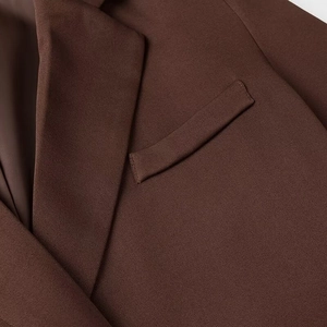 Détail du revers et de la poche poitrine sur blazer en sergé marron avec couture précise
