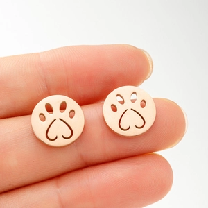 Close-up of rose gold hollow cat paw earrings with heart shaped pads held in hand