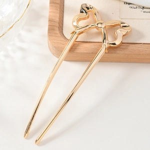 Detailed view of a golden metal U-shaped hair pin featuring a sweet bow design