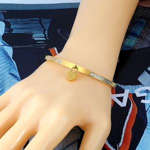 Golden stainless steel bangle with double row of crystals and heart charm on wrist