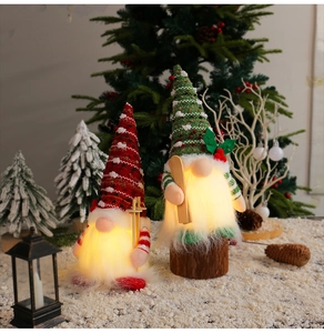 Gnomi di Natale a LED luminosi con cappelli in maglia rossi e verdi su sfondo di neve
