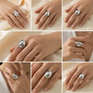 Multiple views of silver teardrop stainless steel ring displayed on beige silk