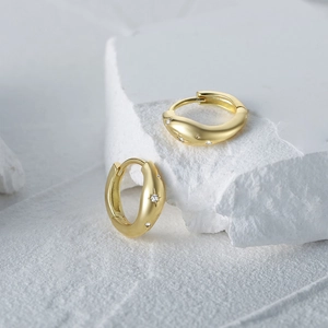 Detailed close-up of gold S925 silver huggie earrings with engraved sparkling star patterns