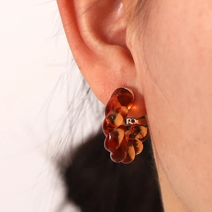 Brown twisted resin C-shaped hoop earrings on model featuring amber translucent finish
