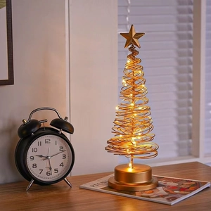Golden iron Christmas tree table lamp with warm LED lights and star topper on wood desk