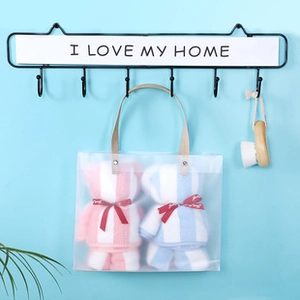 Close-up of bear-shaped coral fleece towels in clear PVC gift bag with red ribbon