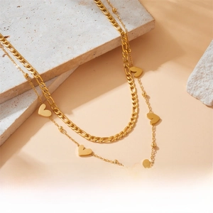 Detail of layered gold stainless steel necklace with heart pendants and Figaro chain