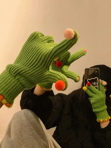 Dettaglio di guanti in maglia verde con pompon colorati e polsini a costine