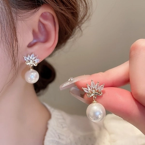 Close-up of gold plated pearl earrings with zircon crown studs on a female model