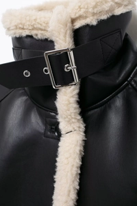 Detail of faux leather jacket collar with beige faux fur trim and adjustable metal buckle