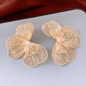 Detailed close-up of golden hollowed-out petal earrings with a minimalist metallic texture