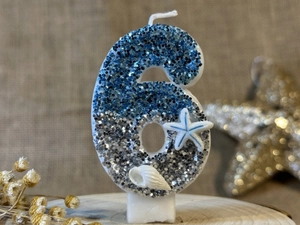 Macro view of ocean-themed blue number 6 birthday candle with starfish and seashell decor