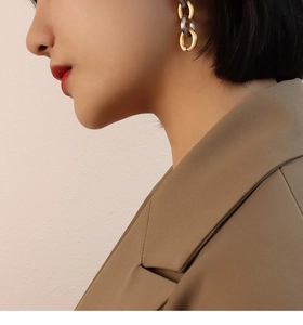 Close-up of stylish two-tone gold and silver link earrings worn by a model