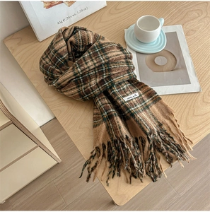 Detailed close-up of brown plaid scarf with fringe tassels on a cozy wooden table