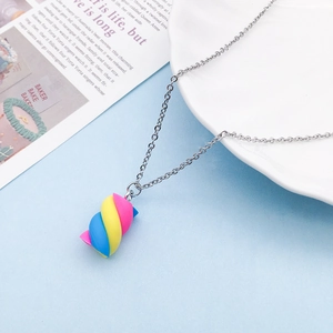 Close-up of pastel resin marshmallow pendant on a silver necklace over blue backdrop