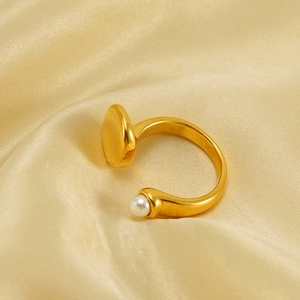 Detailed view of an elegant gold pearl ring resting on smooth champagne silk fabric