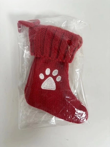 Red knitted Christmas stocking with white paw embroidery in clear plastic packaging