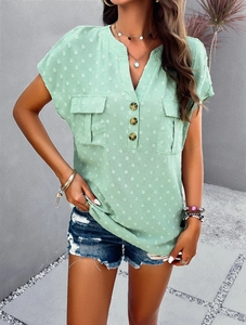 Detail of mint green V-neck shirt featuring textured fabric, buttons, and chest pockets