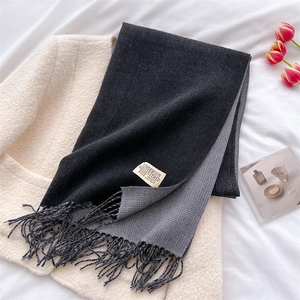 Detail of black and grey double-sided cashmere scarf with fringe and brand label