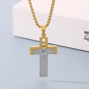 Close-up of two-tone stainless steel cross necklace with engraved English scripture