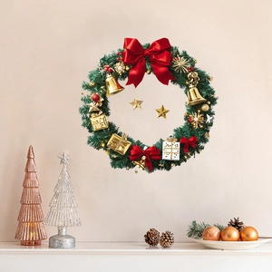 Festive Christmas wreath with red silk bow and gold bells on a cozy white wall background