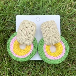 Detailed macro view of bohemian handmade raffia woven earrings in multi-color geometry