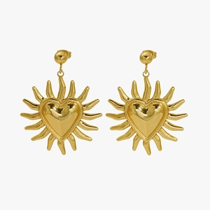 Gros plan sur des boucles d'oreilles vintage dorées avec cœur et rayons de soleil