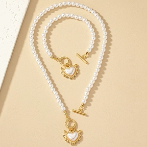 Baroque pearl jewelry set with heart-shaped pendant and OT toggle clasp on beige background