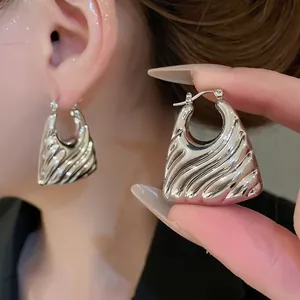 Polished silver metal hoop earrings with wide wavy texture and glossy liquid finish