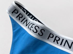 Macro shot of blue cotton thong featuring a PRINCESS lettered elastic sports waistband