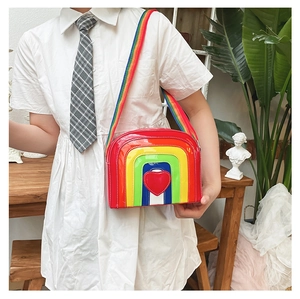 Detail of glossy rainbow heart crossbody bag with matching wide woven strap