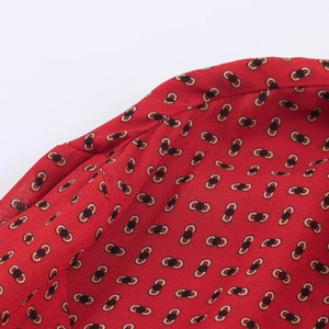 Détail du tissu en mousseline rouge avec motifs de chaînes vintage noir et or