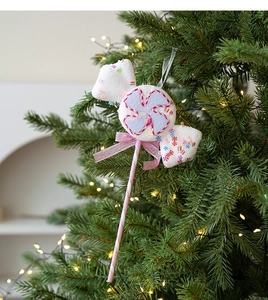 Close-up of pink lollipop Christmas ornament with bow hanging on a festive tree branch