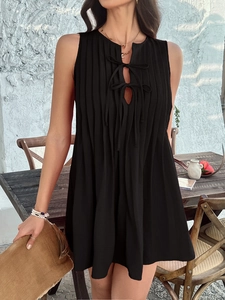 Detail of black sleeveless mini dress with pleated fabric and tie-neckline for women