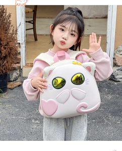Close-up of cute white cat shell backpack featuring yellow reflective mirror eyes for kids