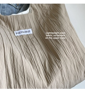 Detailansicht der Knitteroptik und des Markenetiketts an einer khakifarbenen Tasche