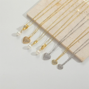 Detailed view of heart pendant and pearl necklaces on a beige travertine stone surface