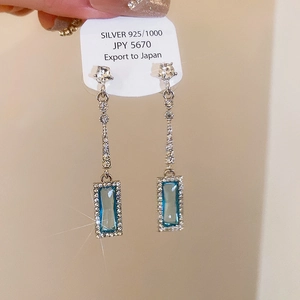 Detailed shot of long silver 925 tassel earrings with blue rectangular zircon gemstones