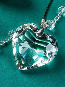 Macro shot of faceted heart-shaped crystal pendant with metallic enamel cross details